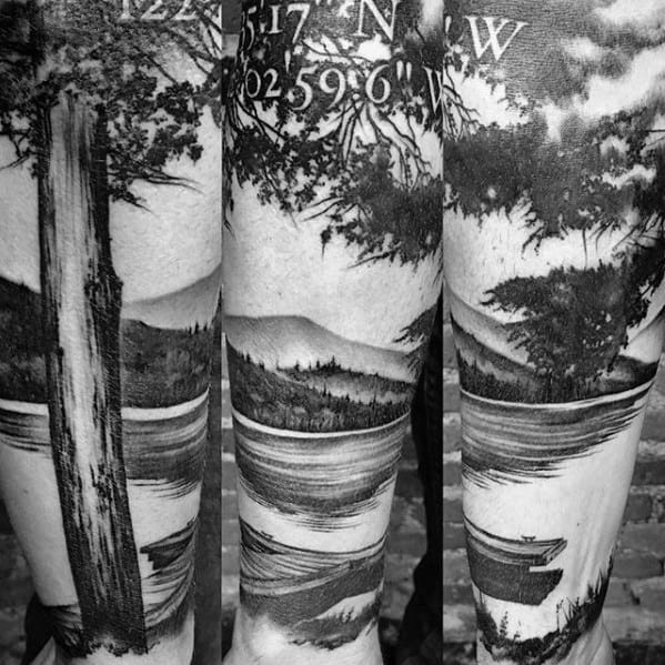 Black and grey leg sleeve tattoo of a peaceful lake with tree-lined shores, mountain views, a canoe, and coordinates etched above.
