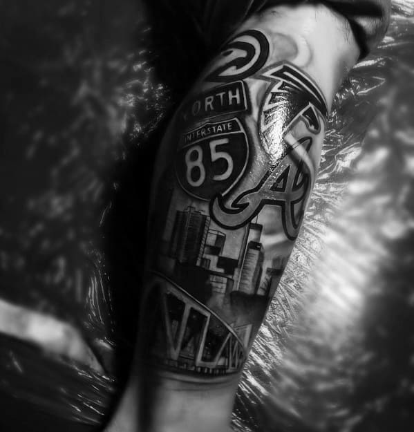 Detailed black and gray tattoo featuring Atlanta skyline, I-85 sign, Falcons, Braves, Hawks logos, and a tribute to the city’s culture.