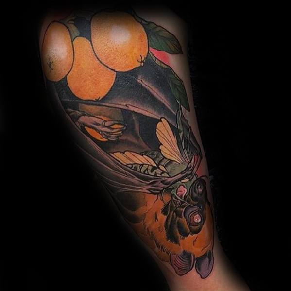 Neo-traditional tattoo of an upside-down bat with oranges, green leaves, and a butterfly tucked in its folded wings.