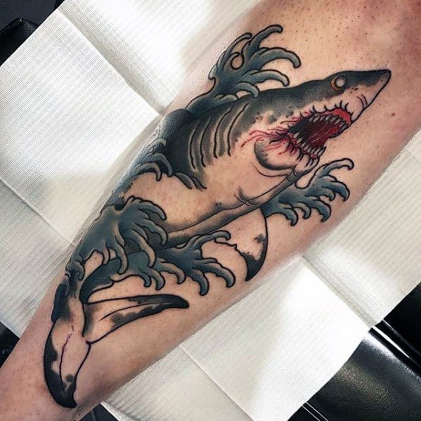 Neo-traditional shark tattoo on the leg with crashing blue waves, blood around the mouth, and bold black outlines.