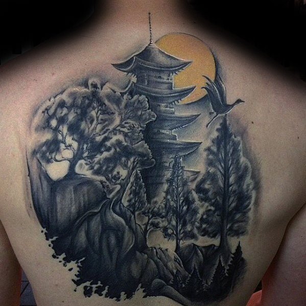 Back tattoo of a Japanese pagoda surrounded by trees, a flying crane, and a large orange sun, blending nature with traditional architecture.