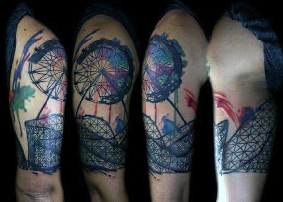 Ferris wheel and roller coaster tattoo with vibrant watercolor splashes in purple, red, and green, wrapping around the upper arm.