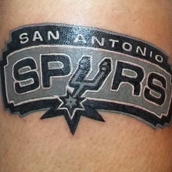 Detailed San Antonio Spurs logo tattoo in black, gray, and white with bold lettering and a stylized spur in the center.