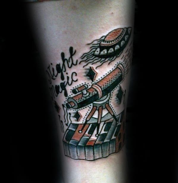 Tattoo of a telescope on piano keys with a spaceship and "Night Music" text