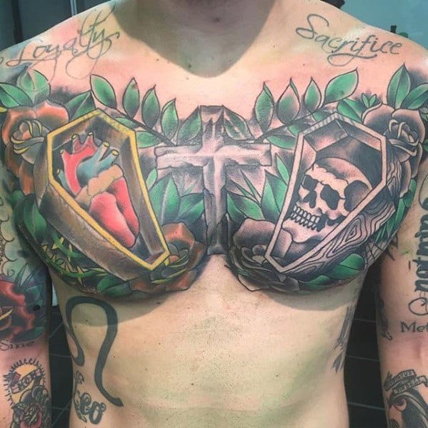 Colorful chest tattoo featuring a stone cross at the center, a heart in a coffin on the left, a skull in a coffin on the right, and green leaves with roses surrounding both, with the words “Loyalty” and “Sacrifice” above.