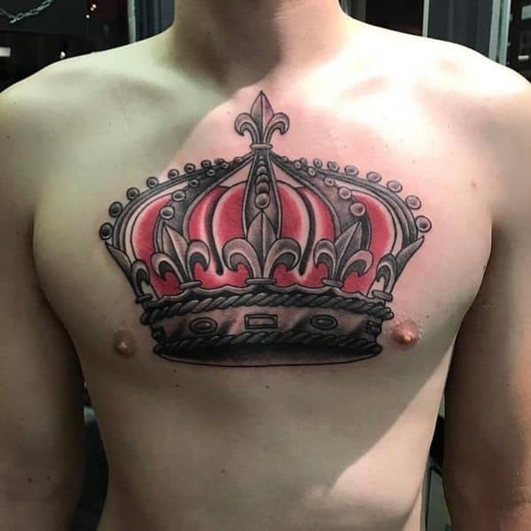 Large chest tattoo of a royal crown in red and black with fleur-de-lis details, bold outlines, and symmetrical shading.