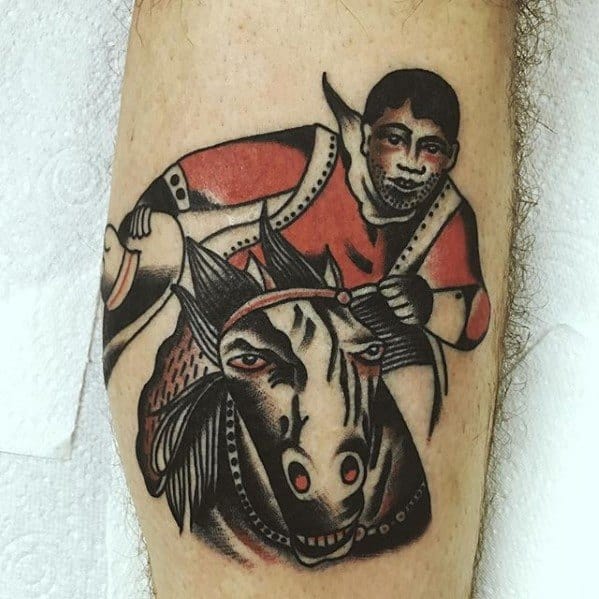 Traditional tattoo of a determined rider in red gear gripping the reins of a fierce black horse with bold eyes and stylized shading.