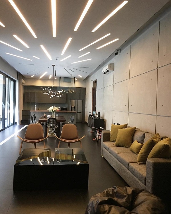 The ceiling features unique, linear LED lighting that radiates outward, creating a bold, modern focal point in the spacious living room