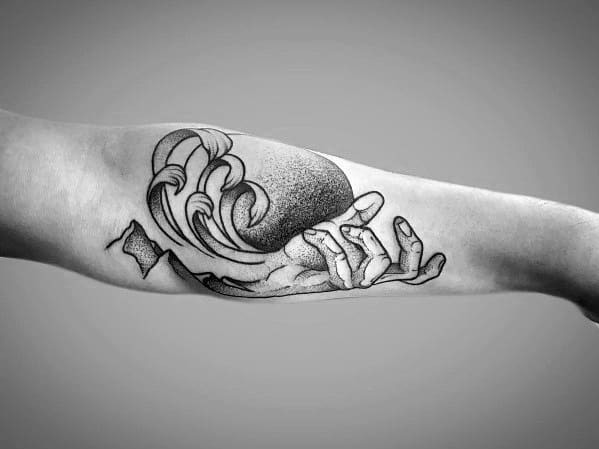 Black ink tattoo of a hand holding a crashing wave, blending realism and abstract elements to symbolize control, nature, and fluidity.