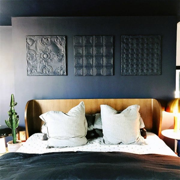 Modern navy-blue bedroom featuring embossed wall art and cozy neutral bedding.