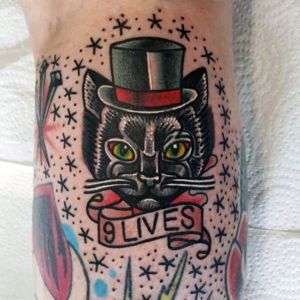 Traditional-style cat tattoo with a top hat, vibrant green eyes, and a '9 Lives' banner, creating a vintage and bold design.