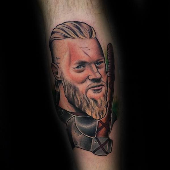 Tattoo of a bearded warrior on an arm with detailed facial features and armor
