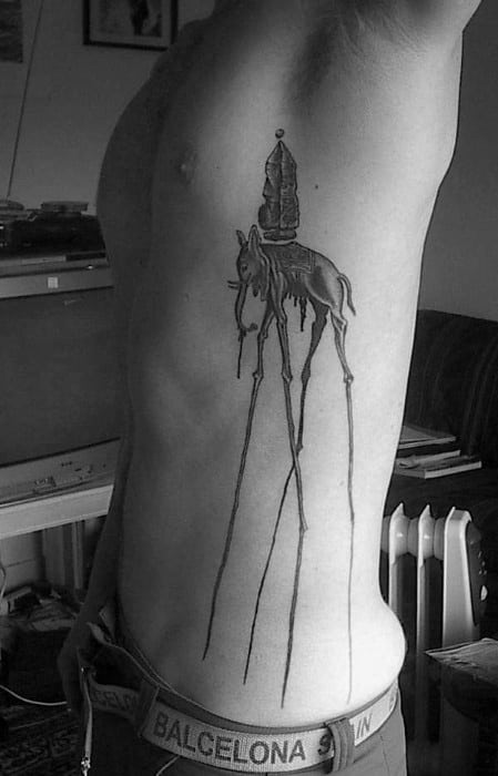Black and grey Salvador Dali-inspired tattoo on the ribcage featuring a surreal elephant with ultra-long legs and an obelisk dripping with detail.