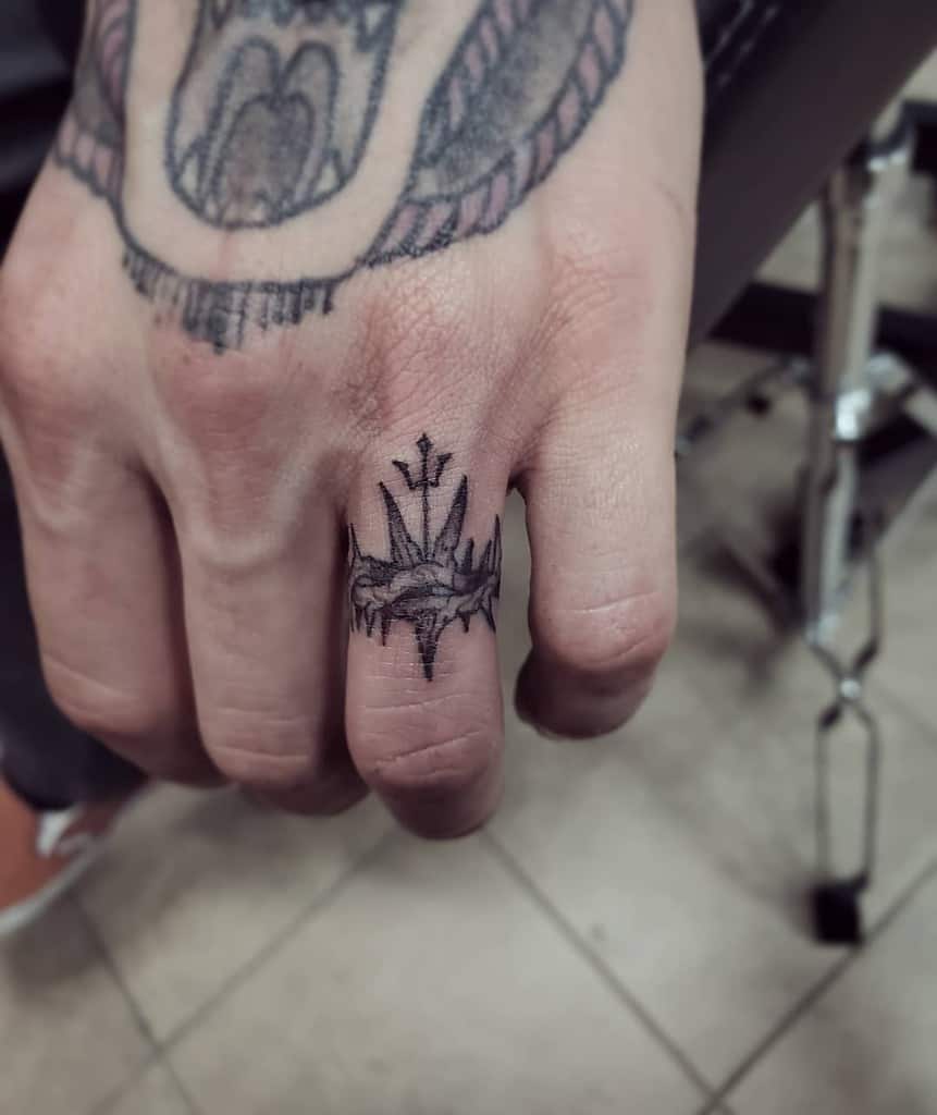 Black ink crown of thorns ring tattoo with trident in its center