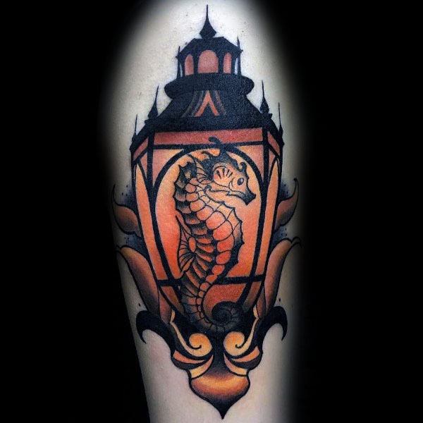 Neo-traditional seahorse tattoo on forearm, featuring bold black outlines, warm orange tones, and a lantern frame for a unique and striking design.