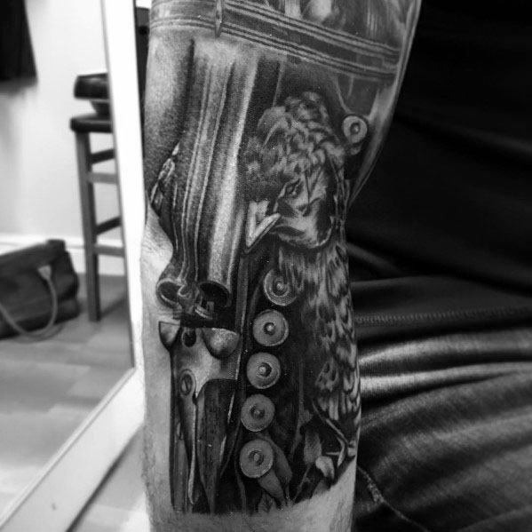 Realistic black and grey tattoo featuring a detailed shotgun, shotgun shells, and a pheasant, creating a bold hunting-themed design with intricate shading.