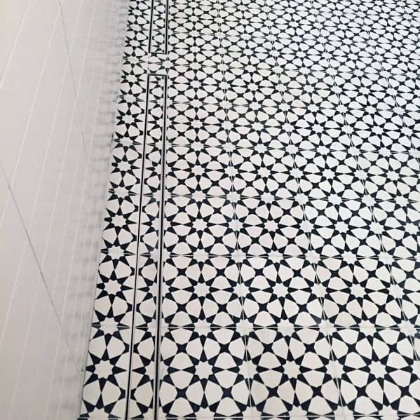 Black and white patterned shower floor with a linear drain along the wall