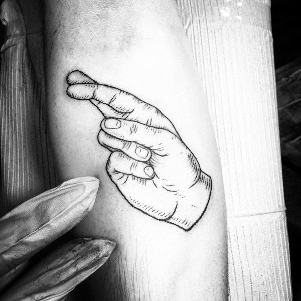 black and grey linework tattoo of a hand making a crossed-fingers gesture, detailed with fine shading and placed on the forearm