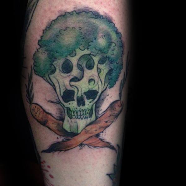 Dark fantasy-style broccoli tattoo with a skull incorporated into the stalk, crossed carrots, and eerie shading for a bold and unique design.