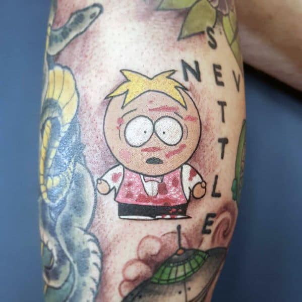 South Park tattoo of Butters in a distressed state, wearing a red vest with bruises and scratches, featuring bold colors and shading.