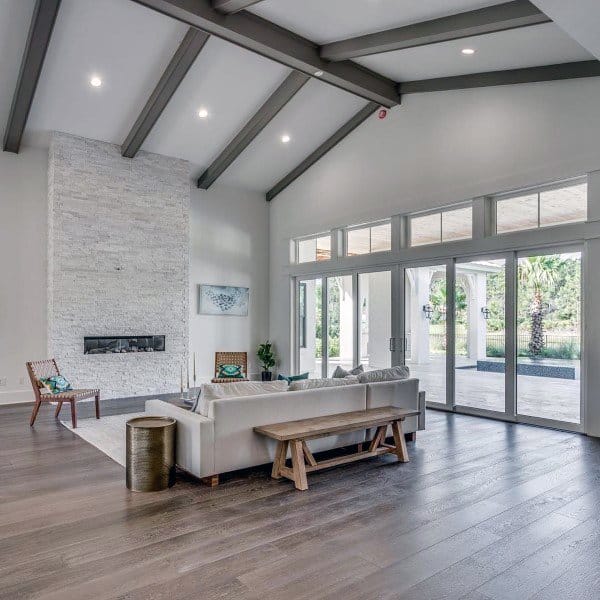 Spacious modern living room with a white stone fireplace, vaulted ceilings, and large glass doors for abundant natural light.