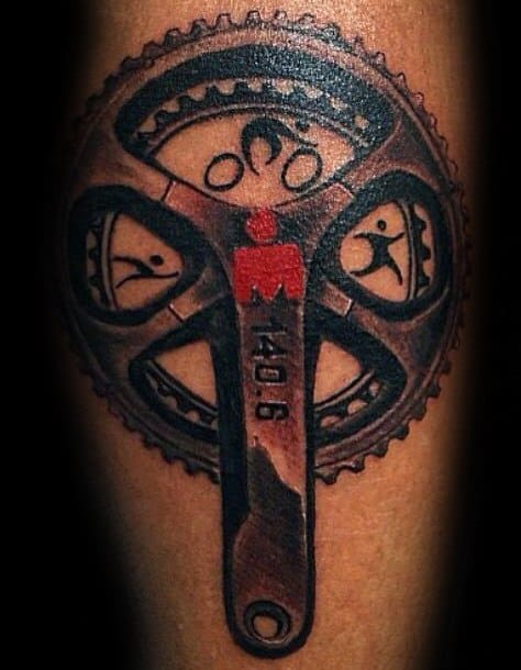 Tattoo design featuring the Ironman logo integrated into a bicycle crankset, symbolizing the endurance and athleticism of the Ironman race with subtle references to swimming, biking, and running.