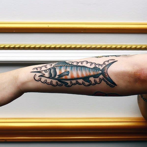 Traditional-style tuna fish tattoo on a man's forearm, featuring bold outlines, vibrant shading, and decorative waves for a classic nautical look.
