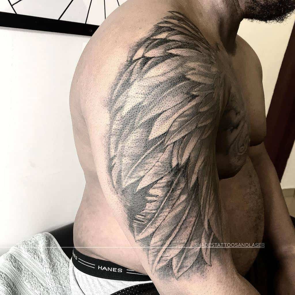 Detailed wing tattoo covering the upper arm and shoulder