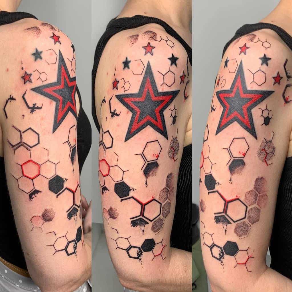 Upper arm tattoo featuring a large red and black star, hexagons, smaller stars, and abstract ink splatters