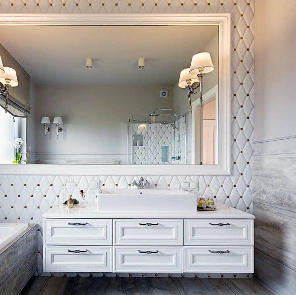 Elegant bathroom with large mirror, white vanity, and sleek wall sconces