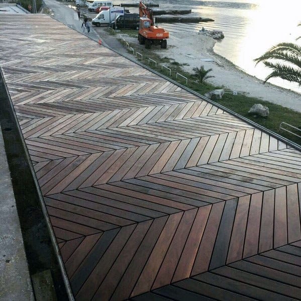 Walkway with chevron pattern by water, next to a construction vehicle