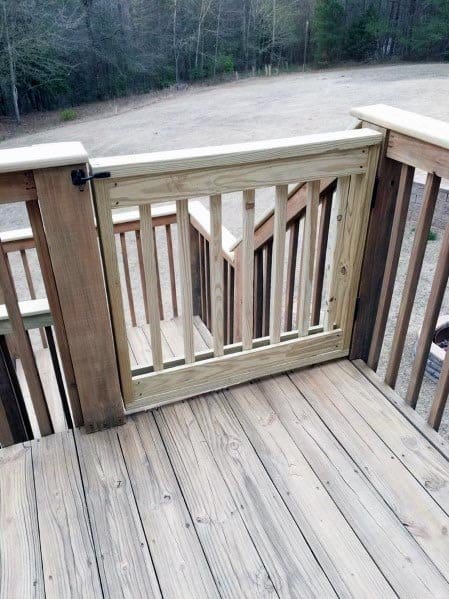 Wooden deck with gate leading to stairs and an open field beyond