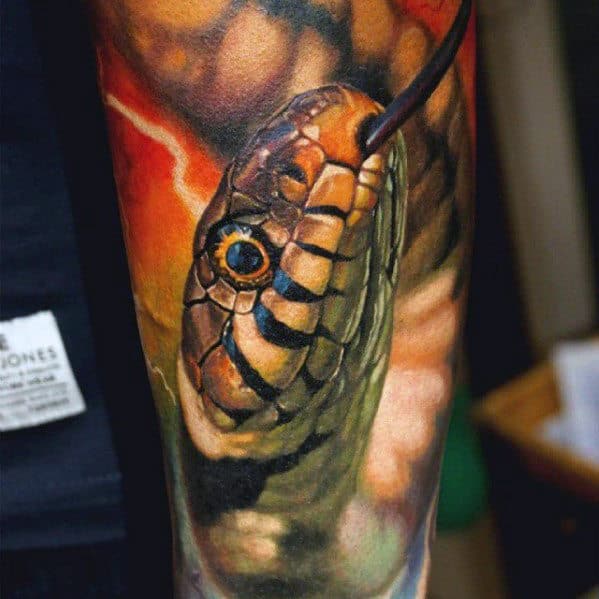 Tattoo of a snake's head with detailed scales and vibrant colors on a person's arm