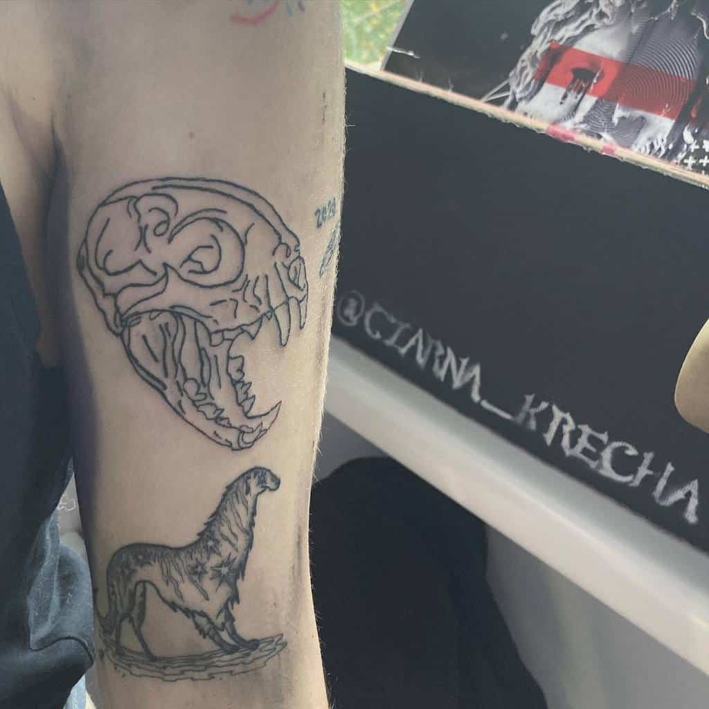 Tattoo of a saber-toothed cat skull on an upper arm