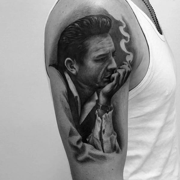 Tattoo of Johnny Cash smoking in black and white on an arm in a sleeveless shirt