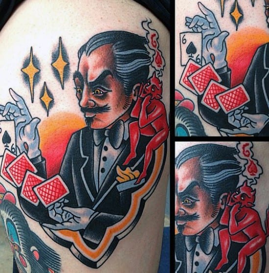 Vibrant tattoo of a magician in a suit performing a card trick with a small red devil whispering in his ear