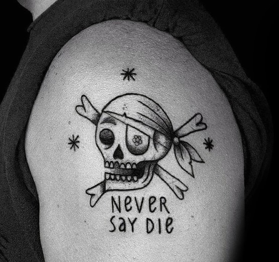 Simple black ink tattoo of a cartoon-style pirate skull and crossbones with a bandana and eye patch, featuring the phrase "Never Say Die."