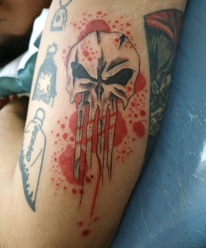 Tattoo of a Punisher Skull with paint splotches on an arm