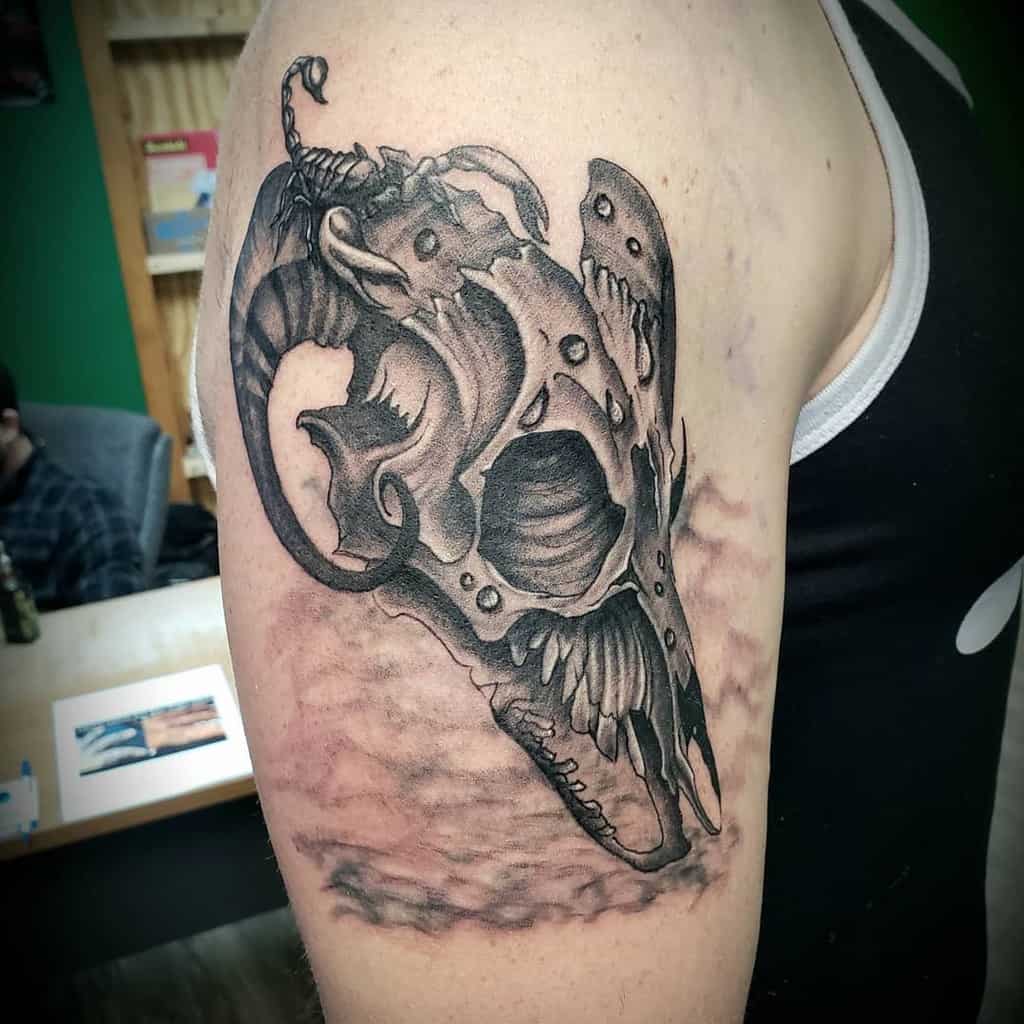 Upper arm tattoo featuring a dark, decayed ram skull with textured details and weathered effects for a haunting look