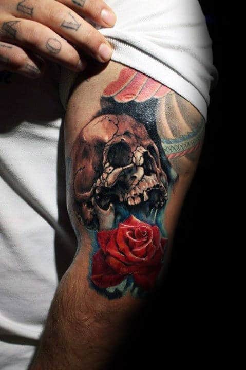 Tattoo of a skull with a vivid red rose on a man's arm