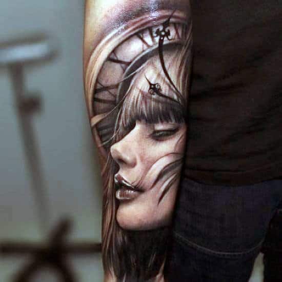 Tattoo of woman's face and clock on forearm