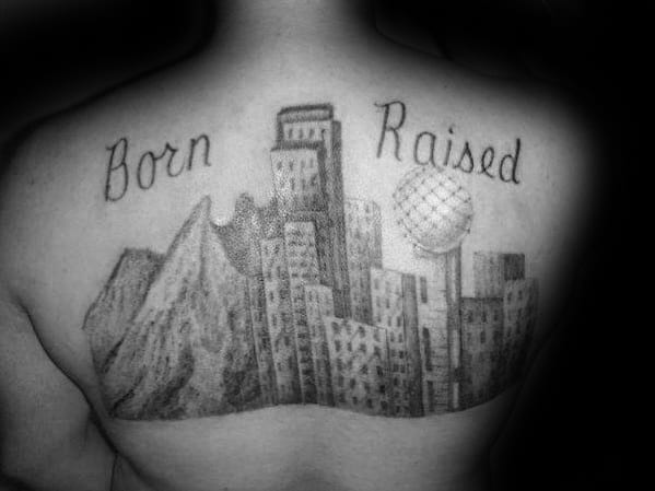 Upper back tattoo of the Dallas skyline with the words "Born" and "Raised" above, shaded in black and gray with detailed buildings.