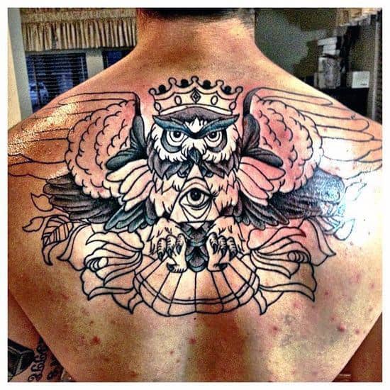 Tattoo of a crowned owl with wings and an all-seeing eye on someone's back