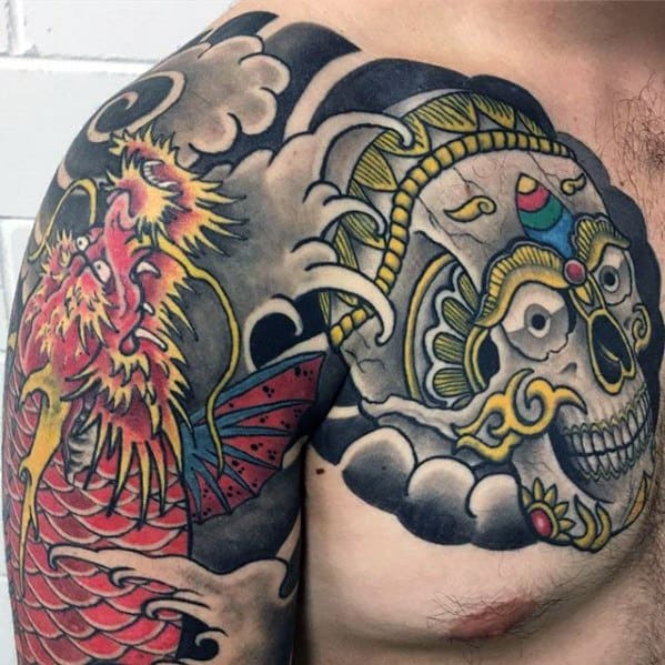 Tibetan skull tattoo on the chest and shoulder with colorful crown, swirling smoke, and a vibrant red and yellow phoenix beside it.