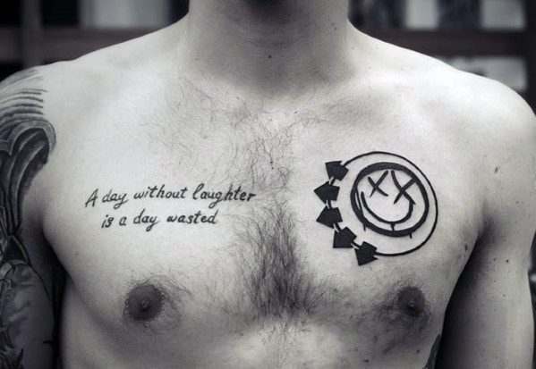Tattoo on the chest with the Blink-182 smiley face logo alongside the quote "A day without laughter is a day wasted," in simple black ink, creating a meaningful and bold design.