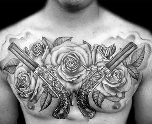 Black and grey chest tattoo featuring ornate crossed pistols surrounded by large, detailed roses and soft shaded background elements.
