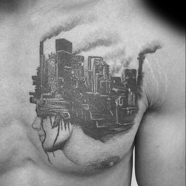 Black and grey chest tattoo of a woman's face blending into an industrial cityscape with smokestacks, symbolizing urban overwhelm.