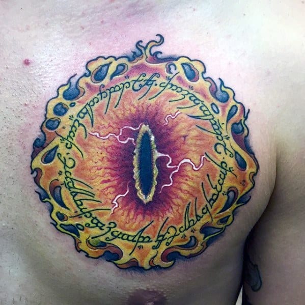 Tattoo of the Eye of Sauron blazing fiercely with mystical scripts encircling it on a person's chest