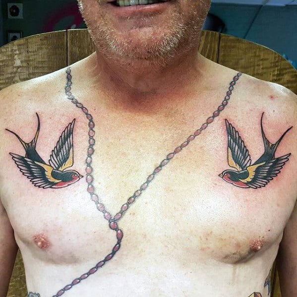 Man with two swallow tattoos and a rosary bead tattoo on his chest