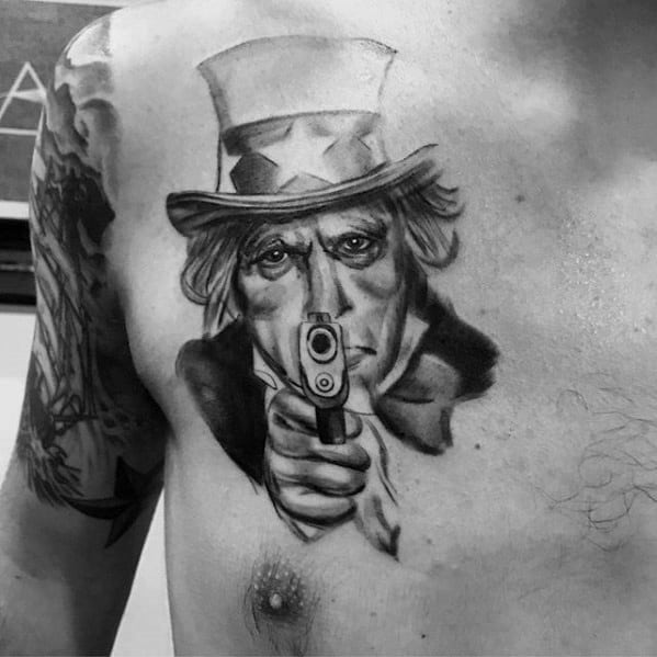 Realistic Uncle Sam chest tattoo in black and gray, with a direct gaze and handgun pointed forward, delivering an intense and commanding vibe.